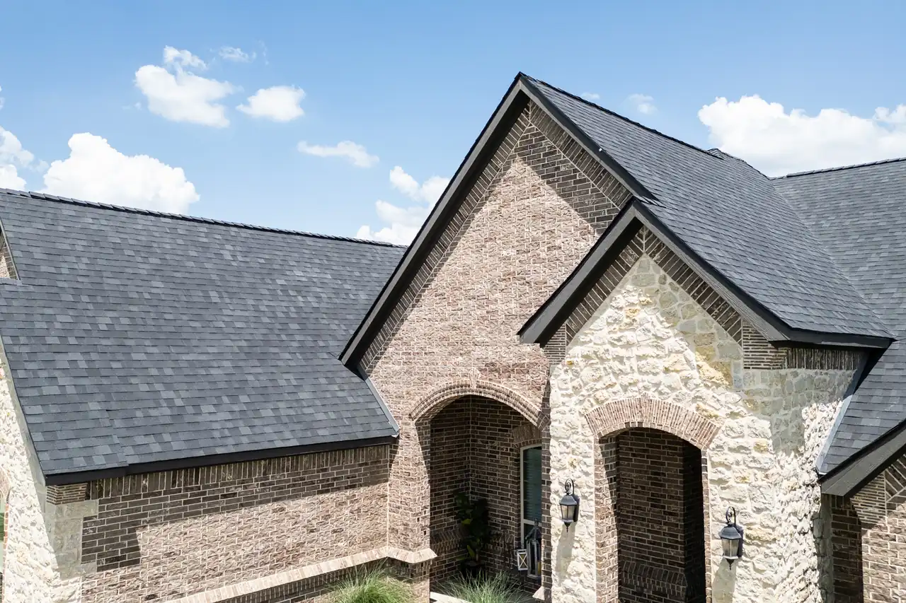 A finished dark architectural shingle roof over the brick and stone gables of a North Texas home