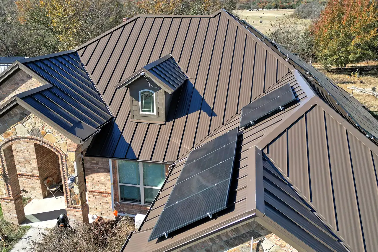 A bronze standing-seam metal roof, its seams and dormer, on a brick and stone home