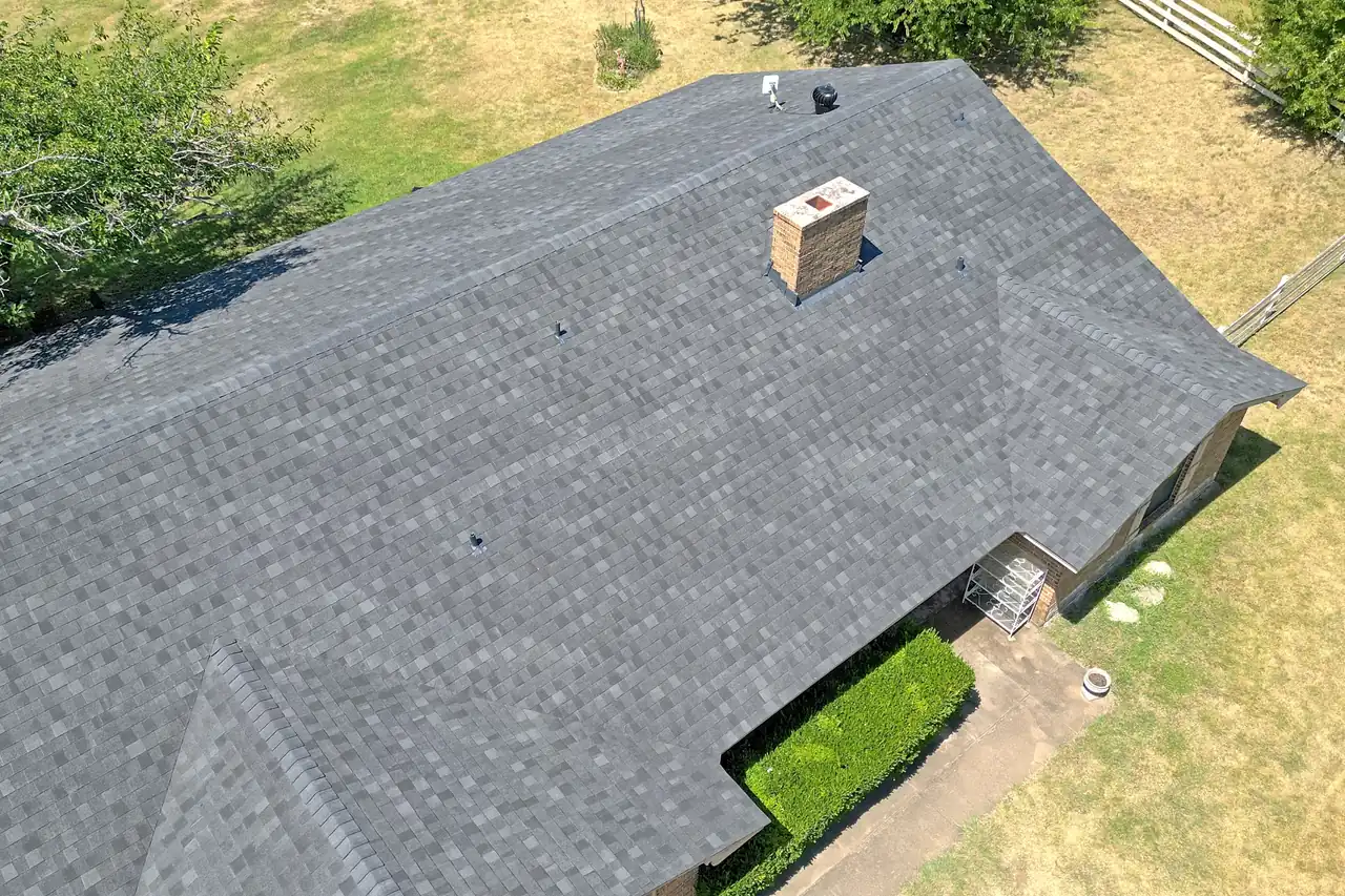 A completed shingle roof replacement seen from above, every plane and valley finished