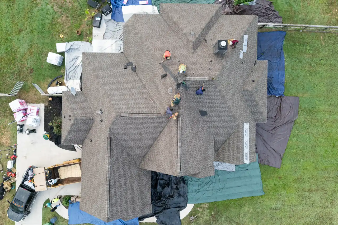 A storm-damaged roof part-way through replacement, the landscaping tarped below